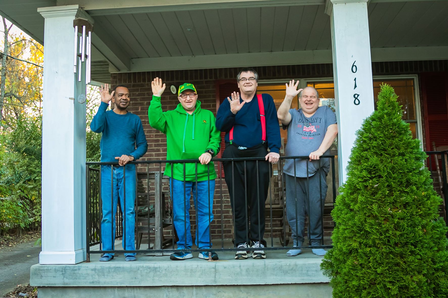 Four people supported by ANCOR member organization standing on a porch and waving at the camera.