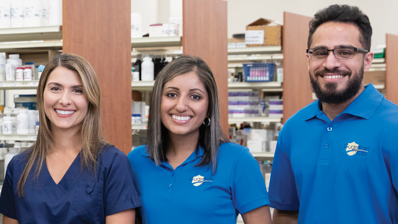 Two women and one man in blue polo shirts smiling at the camera