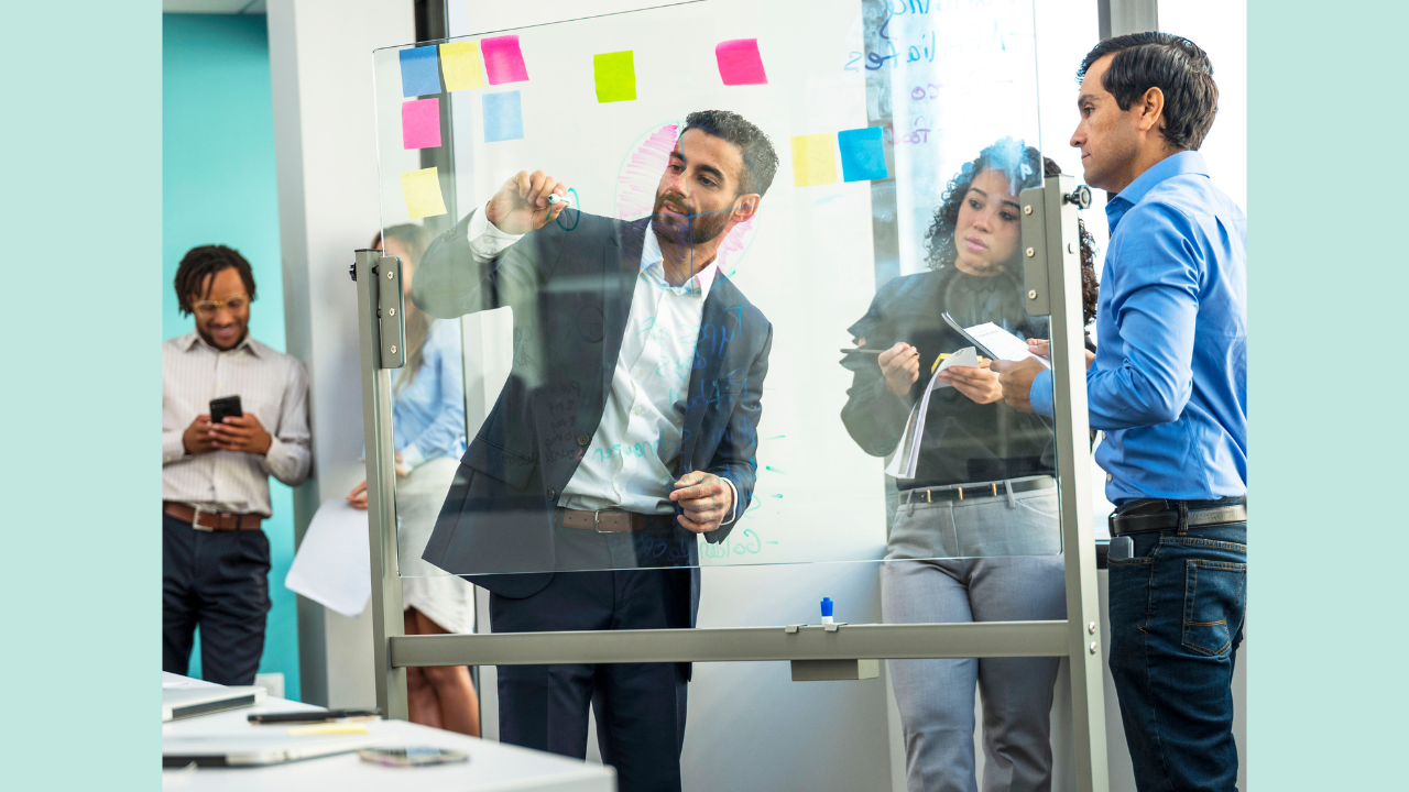 Young professionals collaborating together at a whiteboard using colorful sticky notes.