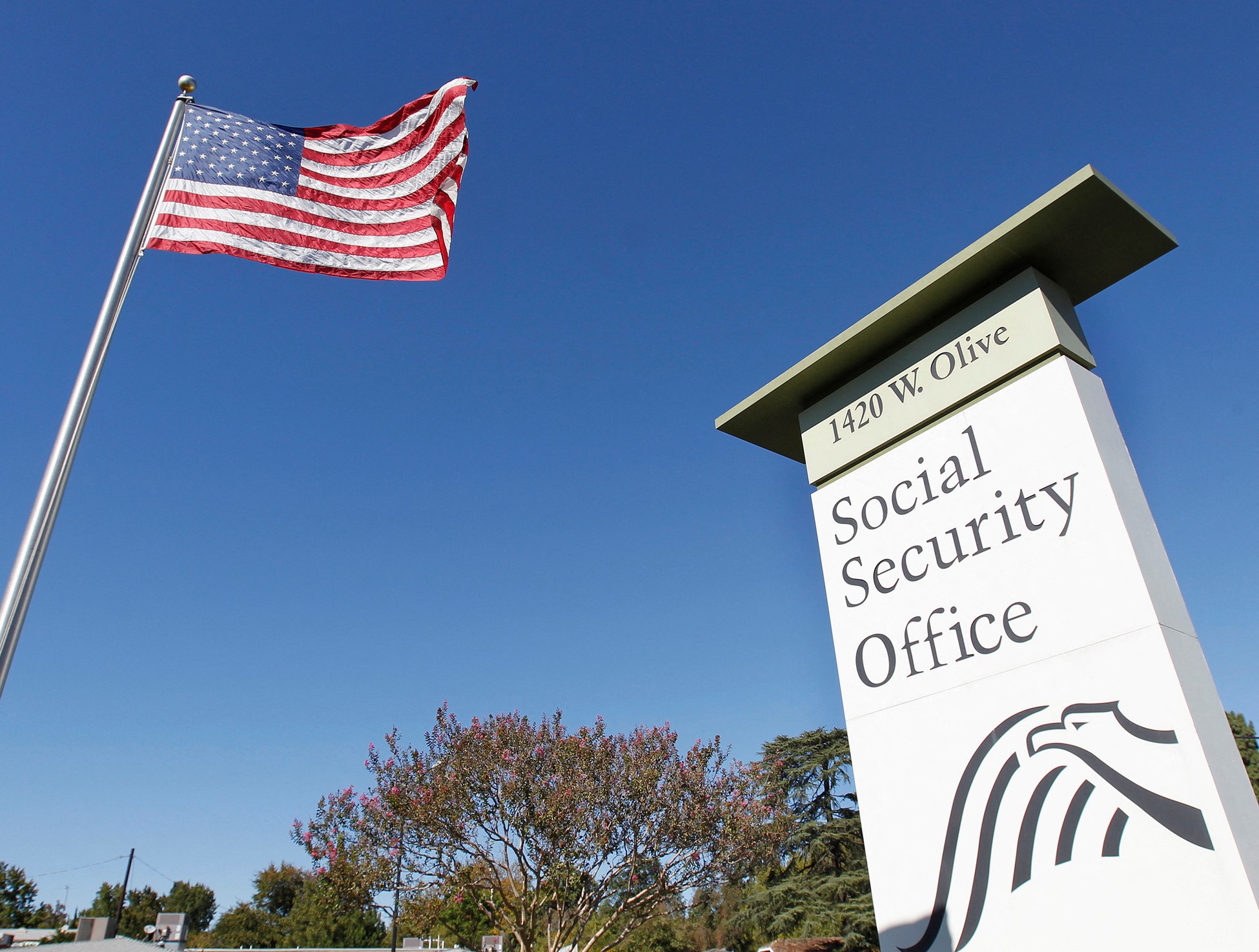 An American flag in the wind next to signage for a United States Social Security Administration office