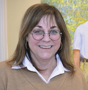 Photo of Karen navel smiling at the camera in front of a painting
