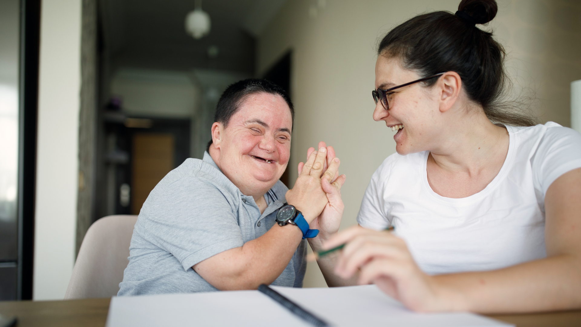 A person with I/DD smiles at their support professional