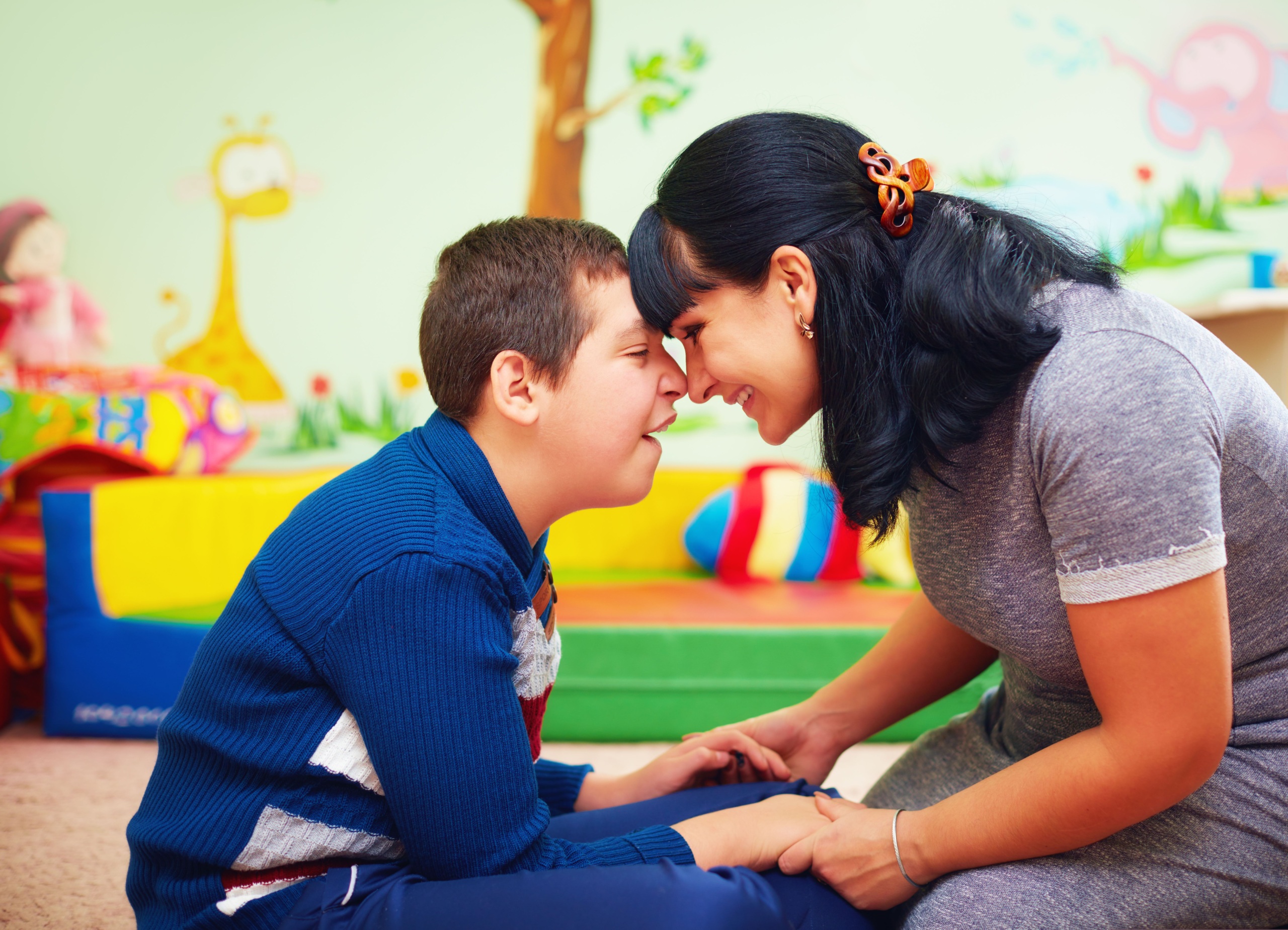 A young person with I/DD smiling while working with therapist