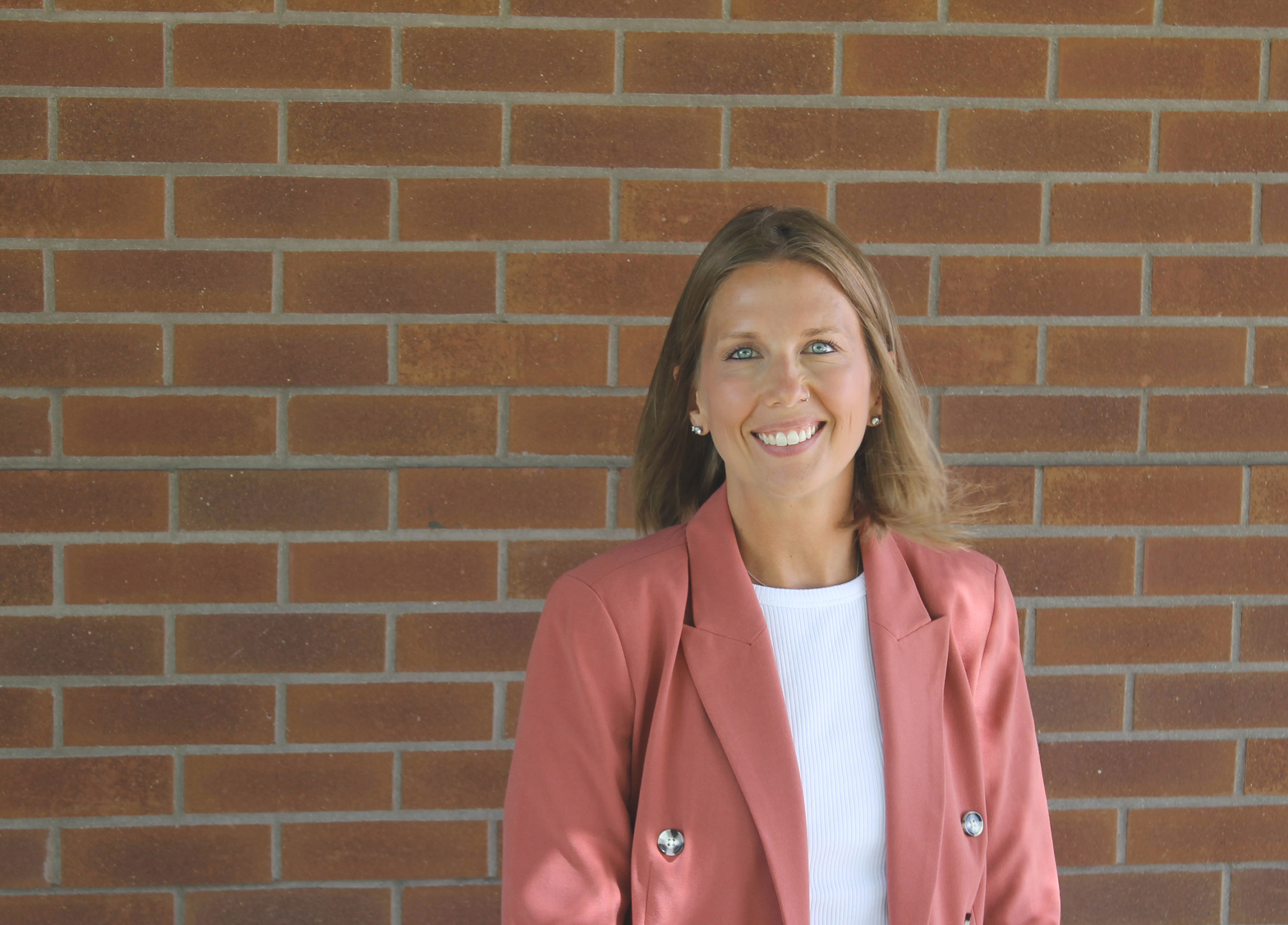 Headshot of Maghan Bowman standing in front of a brick wall.
