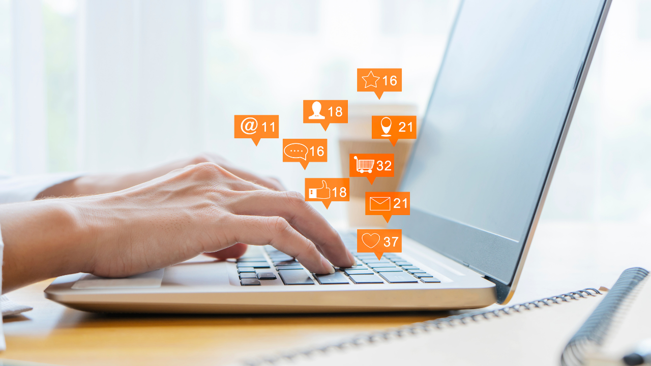 stock photo of hands typing on a laptop with orange notifications floating from the keyboard