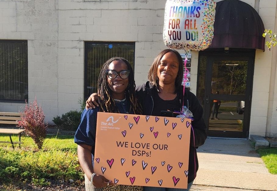 Coworkers hold a sign that says we love our DSPs