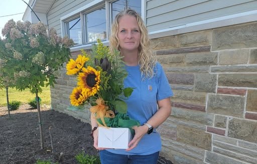 A DSP stands with sunflowers and thank you card