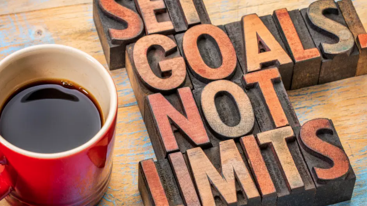 cup of coffee in red mug beside blocks that read 'SET GOALS NOT LIMITS'