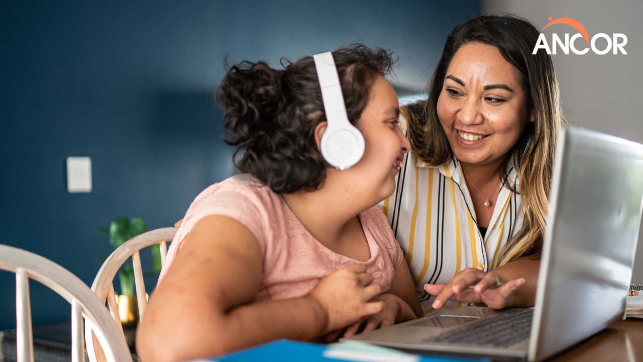 a person with I/DD using a laptop computer with headphones