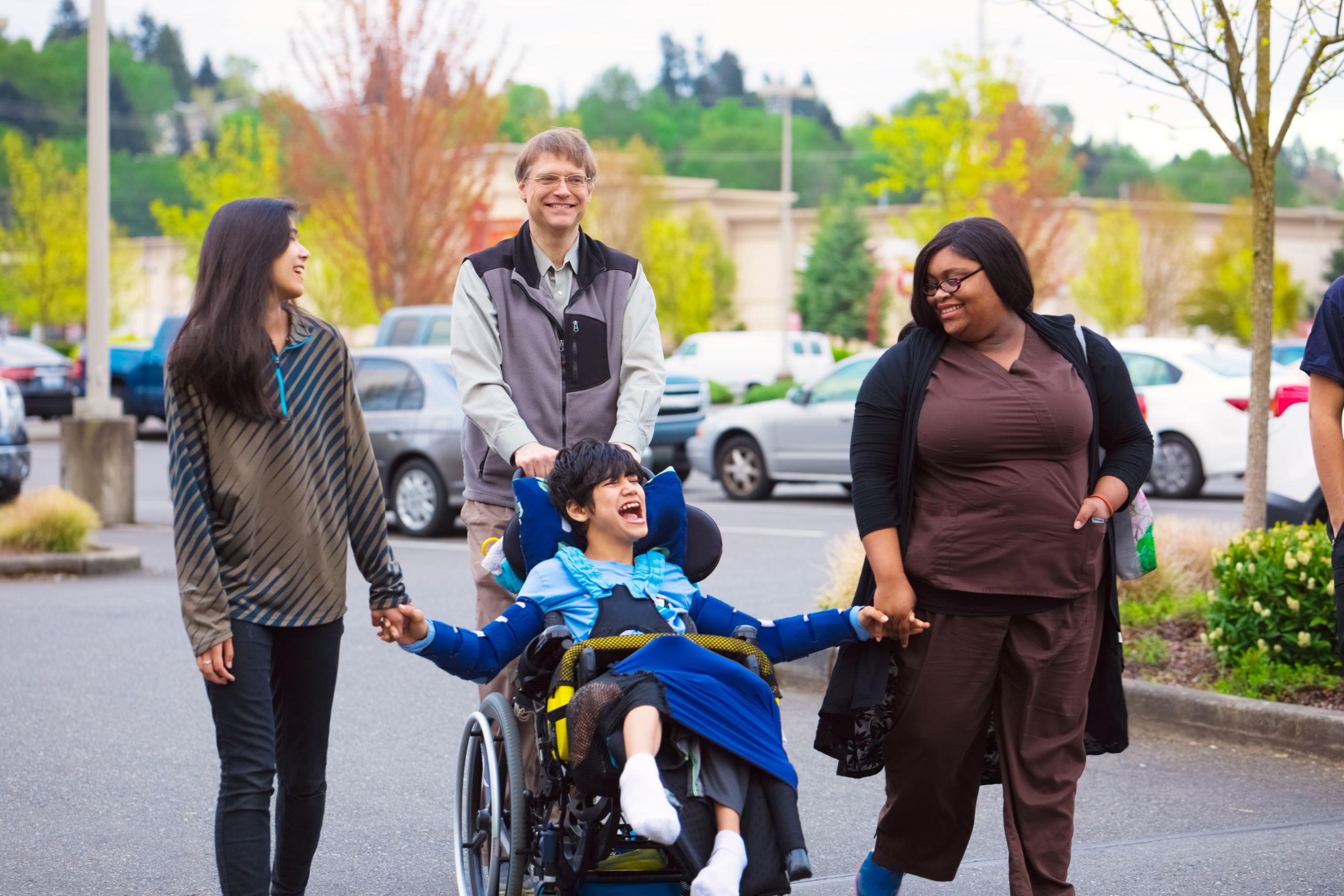 a young person with I/DD laughing with his family and support staff