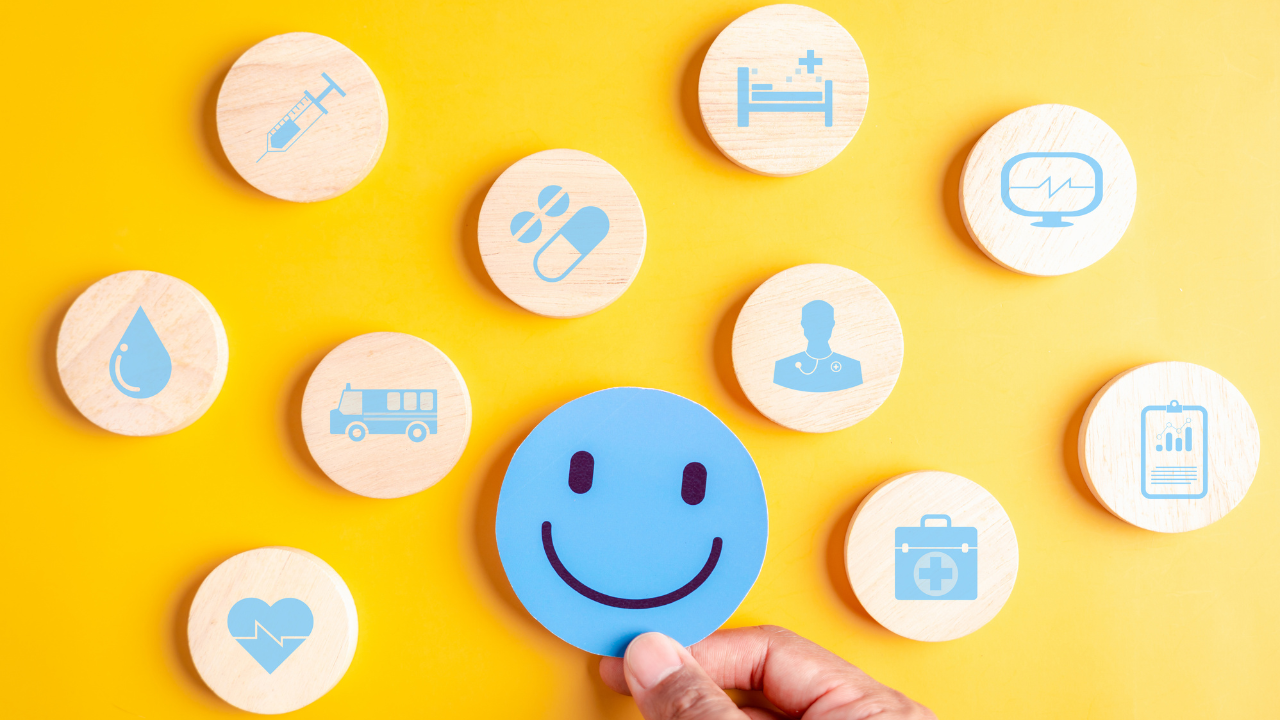 stock photo of a person holding a blue circle cutout of a smiling face surrounded by other circles representing various health car icons