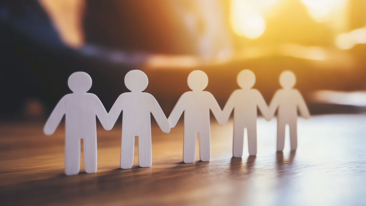 Cut-out people holding hands on top of an office desk