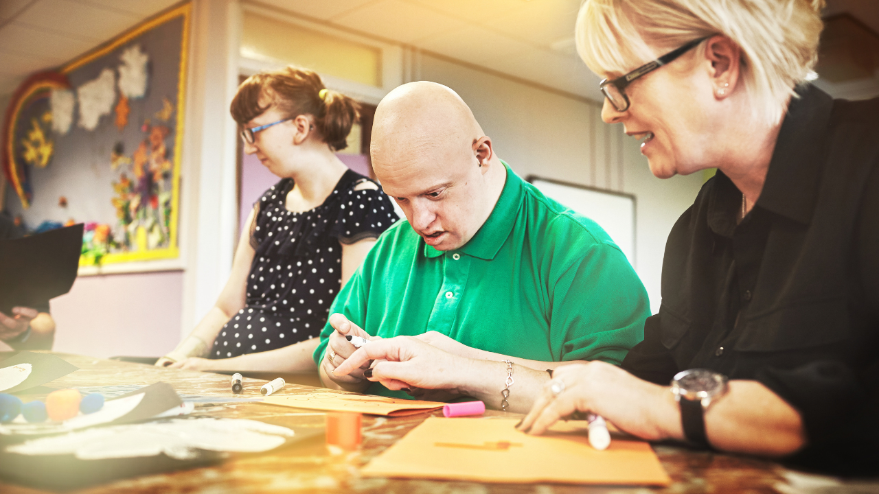 photo of a DSP helping a person with a disability while both sit in front of a table