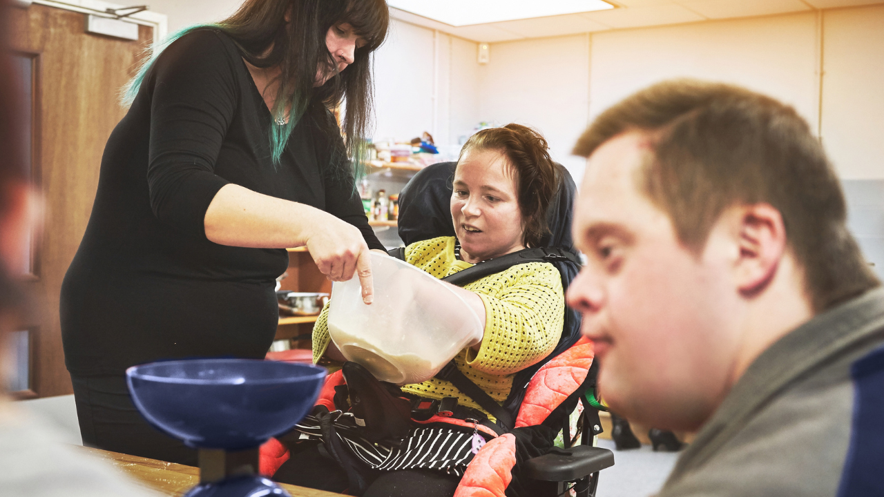 stock photo of a DSP helping two people with disabilities at a table