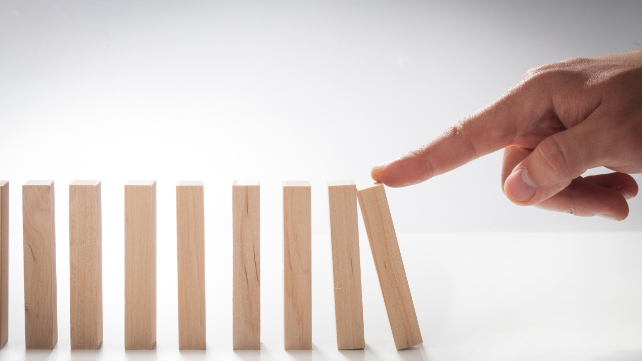stock photo of a finger pushing wooden blocks lined up as dominos